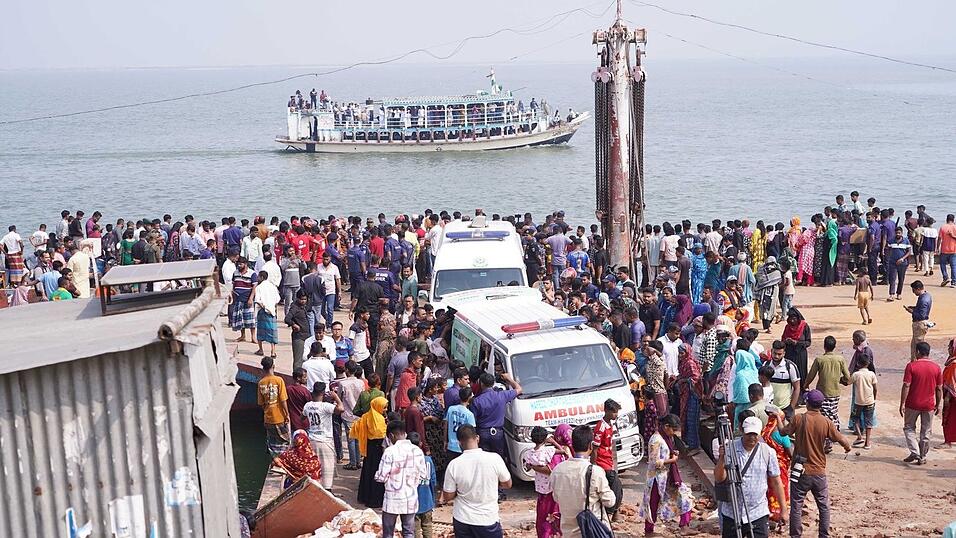 Rettungskr&auml;fte und zahlreiche Menschen versammeln sich an einer Unfallstelle, nachdem ein Bus in den Fluss Padma st&uuml;rzte.