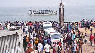 Rettungskr&auml;fte und zahlreiche Menschen versammeln sich an einer Unfallstelle, nachdem ein Bus in den Fluss Padma st&uuml;rzte.