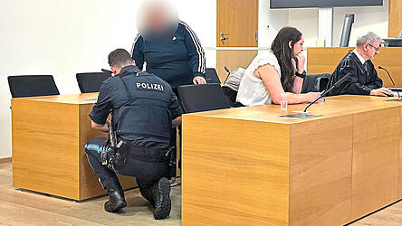 Der Angeklagten werden von einem Beamten die Fu&szlig;fesseln abgenommen. Mit auf dem Bild ihre &Uuml;bersetzerin und ihr Anwalt Stefan Rothneichner.