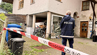 Ein Polizist steht hinter der Absperrung vor dem Mehrfamilienhaus, in welchem die drei Leichen gefunden wurden. 