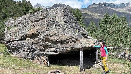 Ursula Scheiber vom Naturpark Ötztal zeigt, wie Steinzeitliche Jäger und Hirten unter überhängenden Felsblöcken am 'Hohlem Stein' bei Vent übernachteten.
