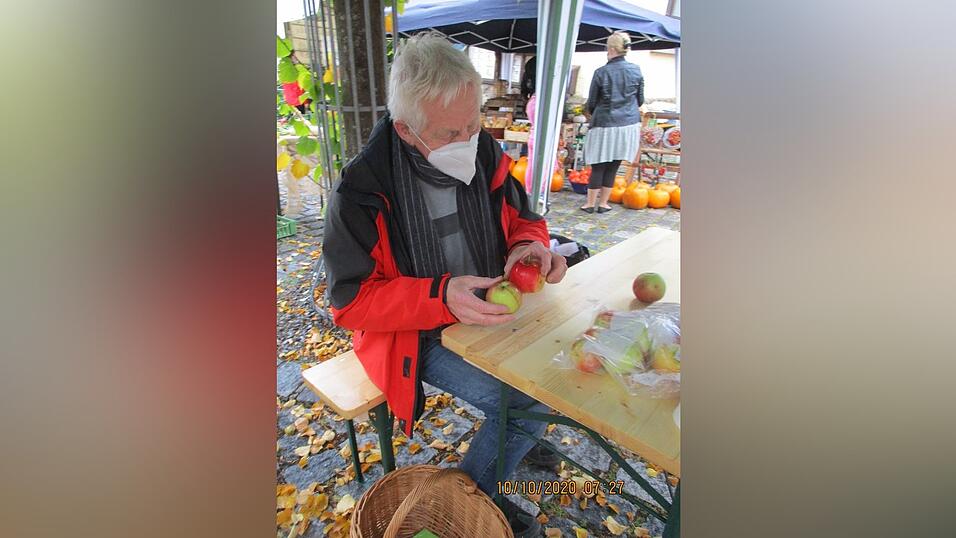 Im Hintergrund warten K&uuml;rbisse auf K&auml;ufer, vorne sitzt Pomologe Wolfgang Subal und hat gut zu tun beim Bestimmen von Apfelsorten.