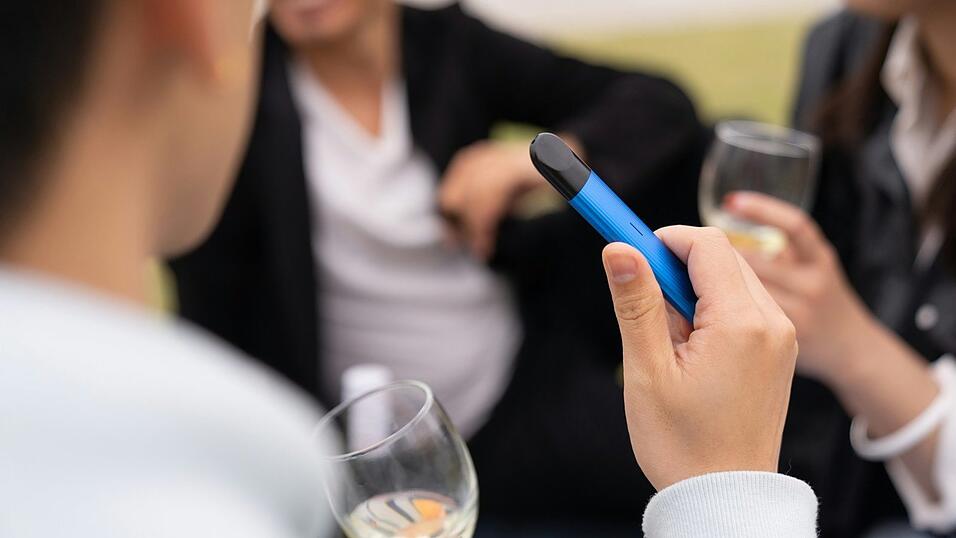 Eine Person beim Umgang mit einer E-Zigarette (Vape)