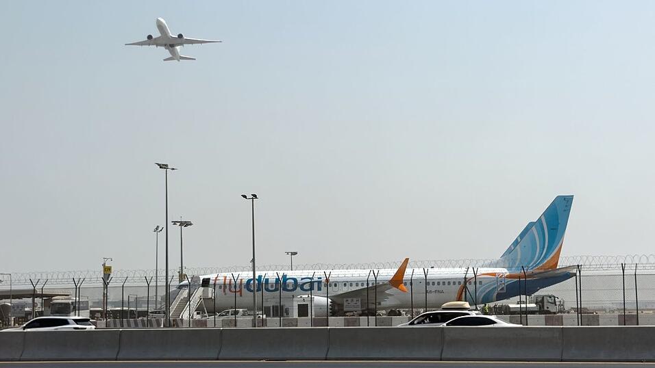 Ein Flugzeug hebt ab, w&auml;hrend ein Flydubai-Flieger in Dubai auf dem Flughafen steht.