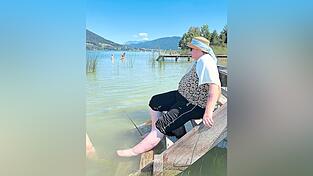 Am Privatstrand von Herbert Mayerhofer erfüllt sich der Wunsch von Anita: Sie sitzt auf einem Holzsteg und hält ihre Füße ins kühle Wasser.