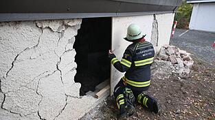 Ein Feuerwehrmann deckt das Loch in der Garagenwand ab. Ein Feuerwehrmann deckt das Loch in der Garagenwand ab.