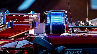 Auf dem Dach eines Einsatzfahrzeugs der Feuerwehr leuchtet ein Blaulicht.