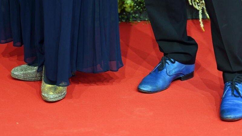 Ein Schauspielerpaar mit blauen und grün-glitzernden Schuhen auf dem roten Teppich. Ein Schauspielerpaar mit blauen und grün-glitzernden Schuhen auf dem roten Teppich.