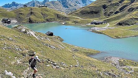 Der Zürsersee glitzert türkis in der Sonne. Ihn erreicht man auf der zweiten Wanderetappe. Anschließend geht es den Hang zum Madlochjoch hoch.