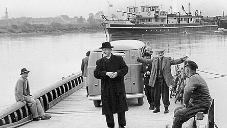 Ein Laden im Auto f&auml;hrt auf einer F&auml;hre &uuml;ber die Donau: die Donauf&auml;hre mit dem fahrbaren B&auml;ckerladen auf dem Weg nach Illkofen. Auf dem Bild Pfarrer Georg Fleischmann (Illkofen) und links, sitzend, Karl Bierschneider senior.