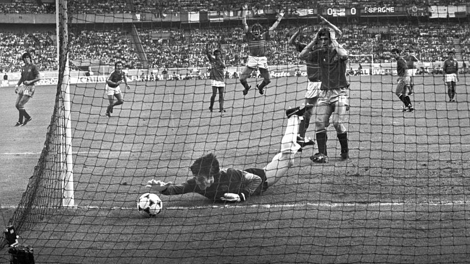 Paris, 27. Juni 1984 | Der Pokal bleibt in Frankreich! Der Gastgeber schl&auml;gt Spanien im Finale mit 2:0 und holt sich seinen ersten EM-Titel. Der Franzose Michel Platini ist der &uuml;berragende Spieler des Turniers und trifft im Finale einen direkten Freisto&szlig; zum 1:0. Der spanische Torwart Luis Arconda versucht vergeblich, den Ball noch abzuwehren.