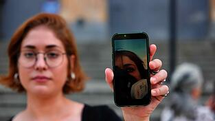 Auf dem Smartphone von Ani Tavazde leuchtet ein Bild, das sie mit Gasmaske w&auml;hrend einer Demo zeigt.