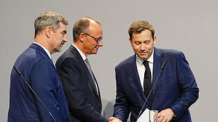 Friedrich Merz (M), Unions-Kanzlerkandidat und CDU-Bundesvorsitzender, und Lars Klingbeil (r), SPD-Fraktions- und Bundesvorsitzender, geben sich nach einer Pressekonferenz zur Vorstellung des Koalitionsvertrages die Hand.