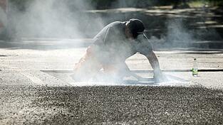 Ein Bauarbeiter repariert eine Stra&szlig;e in Berlin mit Bitumen, einem Bindemittel f&uuml;r Asphalt. (Symbolbild)