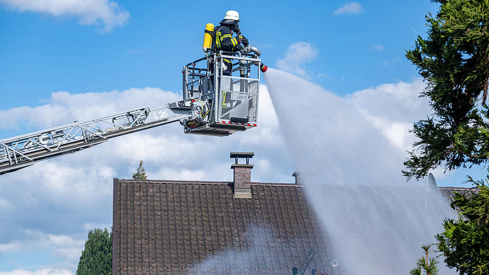Ein Feuerwehrmann l&ouml;scht das Wohnhaus.