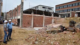Günther Wittmann und Heinfried Ohlmeyer (v. l.) vor ausgehöhlten Mittelschulturnhalle. Im Ostbereich wird künftig im Untergeschoß die Lüftungsanlage ihren Platz finden, darüberliegend der neue Eingangsbereich samt Foyer.