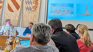 Ein M&auml;nnchen im Spagat neben einem Symbolbild f&uuml;r die Haushaltskasse: Eichendorfs K&auml;mmerer Sebastian Gierl gab vor den Gemeinder&auml;ten und B&uuml;rgermeister Josef Beham (l.) auch heuer keine allzu optimistische Prognose ab, was die Gemeindefinanzen in den kommenden Jahren betrifft.