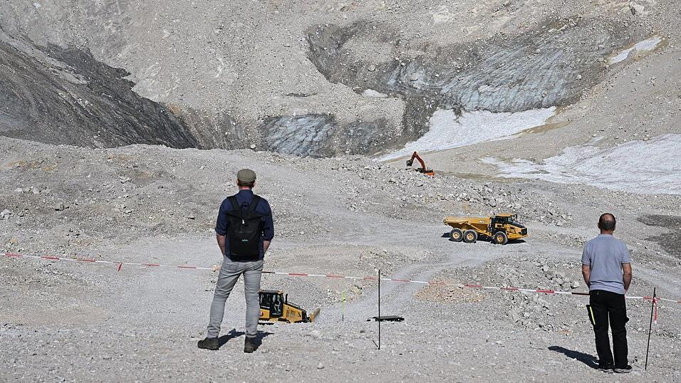 Wanderer beobachten Baumaschinen neben den &Uuml;berresten des N&ouml;rdlichen Schneeferner-Gletschers auf der Zugspitze. (Archivbild)