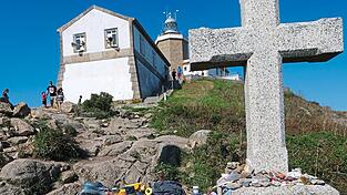 Leuchtturm am Kap Finisterre mit der abgelegten Kleidung und den Schuhen von Pilgern Leuchtturm am Kap Finisterre mit der abgelegten Kleidung und den Schuhen von Pilgern