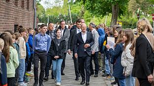 Der geschäftsführende Bundeskanzler Olaf Scholz (SPD, Mitte, r) besucht anlässlich des EU-Projekttages an Schulen das Humboldt-Gymnasium Eichwalde. Neben ihm gehen die Schulsprecher Pia und Pascal.