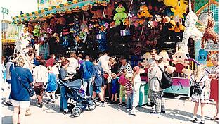 Gro&szlig;er Andrang am Losstand, wo es f&uuml;r vier Mark zehn Lose gab. Man beachte das Schild zwischen den baumelnden Pl&uuml;schraubkatzen am rechten Bildrand: &bdquo;Leute zum Mitreisen gesucht&ldquo; - ein lange Zeit typisches Stellengesuch der Branche.