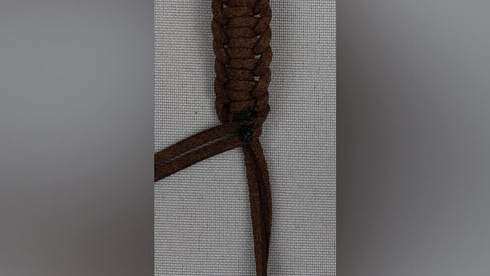 10. Wickle die restlichen Enden des 150-Zentimeter-Bandes um das Armband und verklebe sie fest. Anschließend kannst du die überstehenden Teile abschneiden.