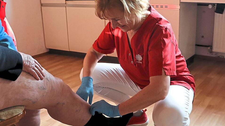Angela K&ouml;hler zieht einer Patientin Kompressionsstr&uuml;mpfe an.