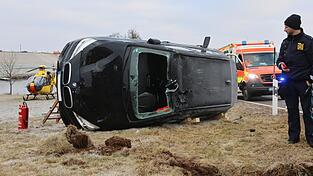 Um die eingeschlossene Frau aus dem Fahrzeug zu befreien, schnitten die Feuerwehrleute die Frontscheibe aus dem BMW. Der Rettungshubschrauber im Hintergrund konnte unverrichteter Dinge abheben, da die 58-Jährige lediglich leichte Verletzungen erlitt und mit dem Rettungswagen ins Krankenhaus kam.