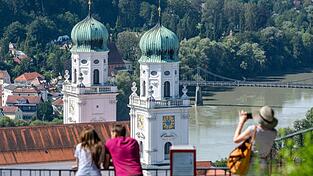 Touristen stehen bei sommerlichen Temperaturen vor dem Dom St. Stephan. (Archivbild)