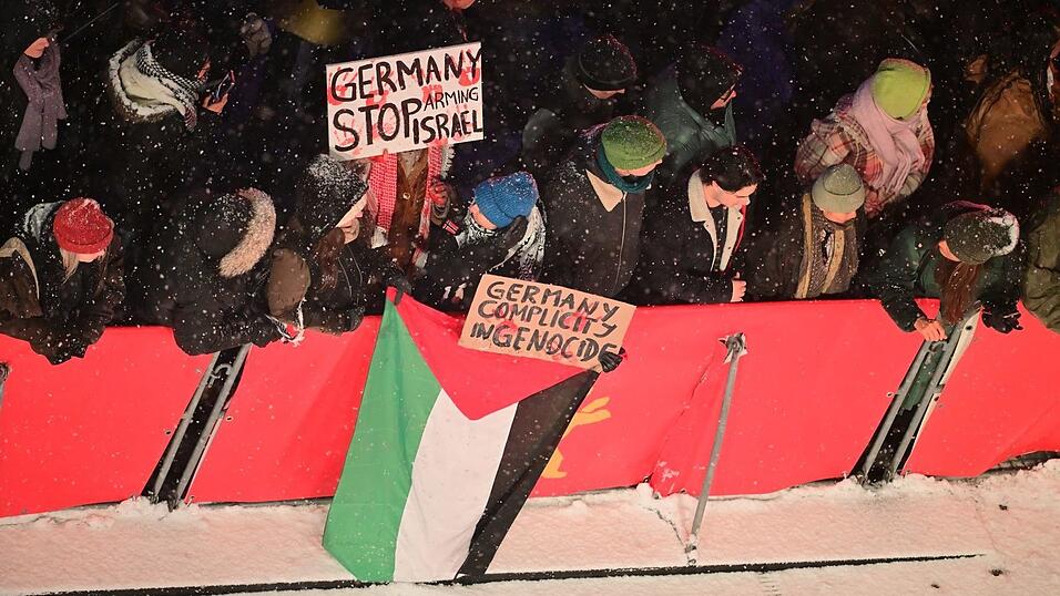 Zuschauer mit propalästinensischen Schildern am Rand des Teppichs.