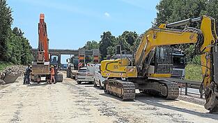 Bauarbeiter warten gerade auf einen der gewaltigen Bagger, die die zerbrochene Betonfahrbahn aus den 1980er-Jahren weiter zertrümmern und dann auf 80-Tonner-Lastwagen verladen.