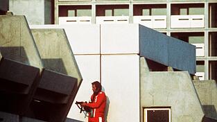 Ein bewaffneter Polizeibeamter im Trainingsanzug sichert am 05.09.1972 im Olympischen Dorf in München den Block, wo Terroristen die israelischen Geiseln festhalten.