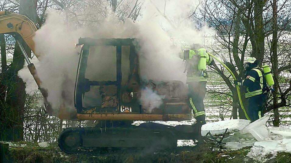 Feuerwehrleute l&ouml;schten unter Atemschutz den brennenden Bagger ab.