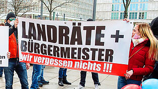 Das Foto zeigt eine Demonstration gegen die Schutzma&szlig;nahmen zur Eind&auml;mmung der Corona-Pandemie auf dem Berliner Alexanderplatz 2022. Ein Transparent mit der Drohung: &bdquo;Landr&auml;te und B&uuml;rgermeister, wir vergessen nichts.&ldquo; Die Corona-Pandemie stellt f&uuml;r viele Kommunalpolitiker einen Wendepunkt dar. Der Umgangston ist seitdem rauer geworden, immer mehr Kommunalpolitiker sind Beleidigungen, Drohungen oder im Extremfall &Uuml;bergriffen ausgesetzt. (Symbolbild)