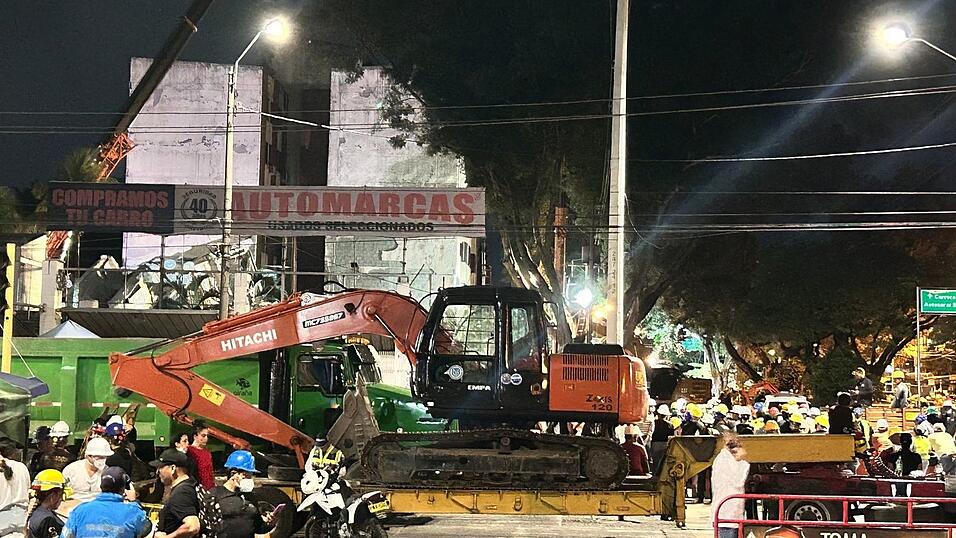 Helfer bringen einen Bagger zu einem eingestürzten Gebäude. Helfer bringen einen Bagger zu einem eingestürzten Gebäude.