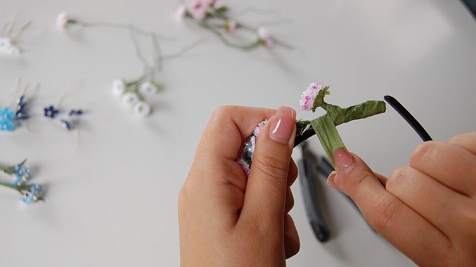 6. Weiter geht's zwischen den Blüten. Auch hier Draht und Haarreif mit dem Klebeband umwickeln. Dazu die Blümchen vorsichtig zur Seite biegen. Wenn das Klebeband aus ist, einfach ein neues Stück abreißen. Am Ende sollen nur die Blümchen auf grünem Untergrund zu sehen sein. 6. Weiter geht's zwischen den Blüten. Auch hier Draht und Haarreif mit dem Klebeband umwickeln. Dazu die Blümchen vorsichtig zur Seite biegen. Wenn das Klebeband aus ist, einfach ein neues Stück abreißen. Am Ende sollen nur die Blümchen auf grünem Untergrund zu sehen sein.