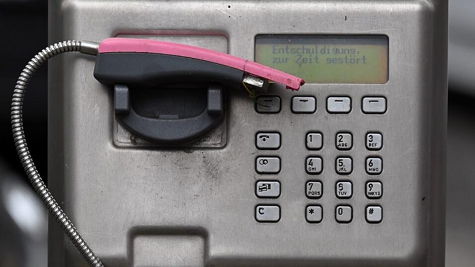 Ein abgebrochener Telefonhörer liegt in der Halterung eines deaktivierten Fernsprechers.