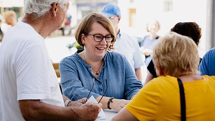 Johanna Schramm, Initiatorin des Bürgerbegehrens gegen den Bau einer Seniorenresidenz auf der Mühleninsel (Mitte), berichtet von durchweg positiven Reaktionen am Stand des Bürgerbegehrens vor dem Rathaus.