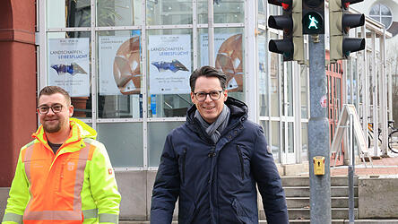 Stadt-Mitarbeiter Florian Geiger und Oberb&uuml;rgermeister Dr. Moser (r.) testen die neue Fu&szlig;g&auml;ngerampel mit Kn&ouml;delwerferin-Motiv am &Ouml;stlichen Stadtgraben.