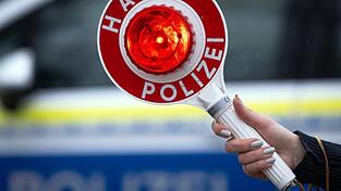Eine Polizistin hält während einer Verkehrskontrolle eine Polizeikelle mit der Aufschrift „Halt Polizei“ Eine Polizistin hält während einer Verkehrskontrolle eine Polizeikelle mit der Aufschrift „Halt Polizei“
