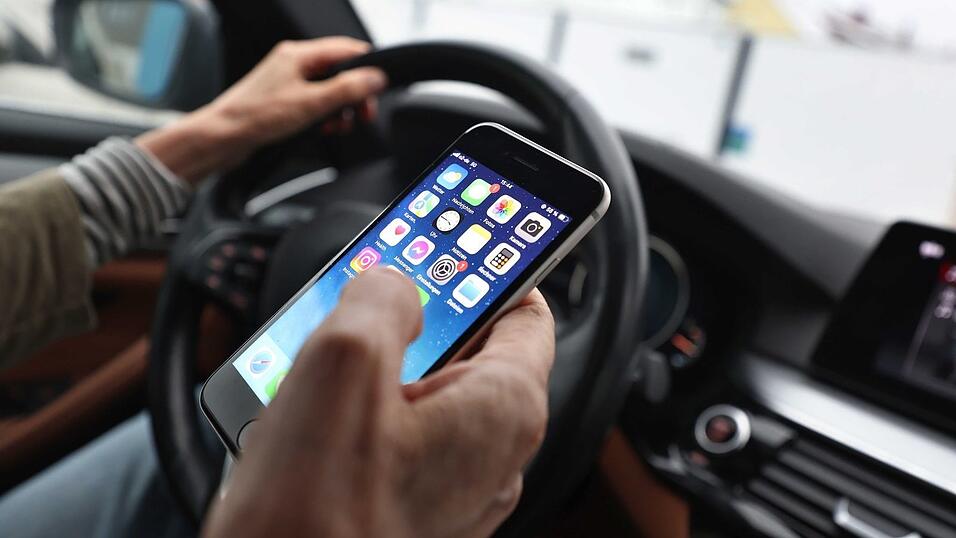 Sorgt für Ablenkung beim Fahren und dadurch immer wieder für Unfälle: das Smartphone am Steuer. (Illustration) Sorgt für Ablenkung beim Fahren und dadurch immer wieder für Unfälle: das Smartphone am Steuer. (Illustration)