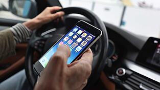 Sorgt f&uuml;r Ablenkung beim Fahren und dadurch immer wieder f&uuml;r Unf&auml;lle: das Smartphone am Steuer. (Illustration)