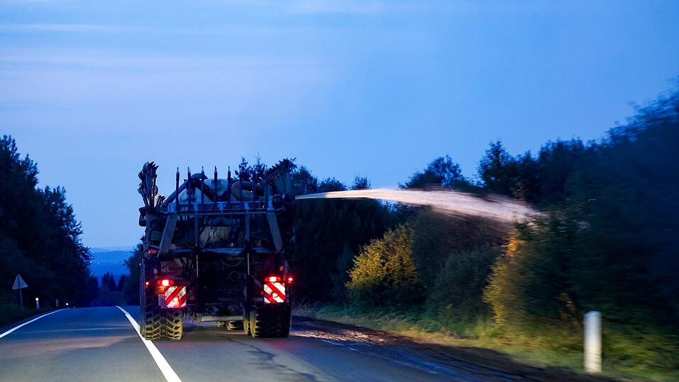 Ein landwirtschaftliches Fahrzeug wässert den Straßenrand mit Wasser aus dem Tank hinter seinem Traktor gegen die Flammen. Ein landwirtschaftliches Fahrzeug wässert den Straßenrand mit Wasser aus dem Tank hinter seinem Traktor gegen die Flammen.