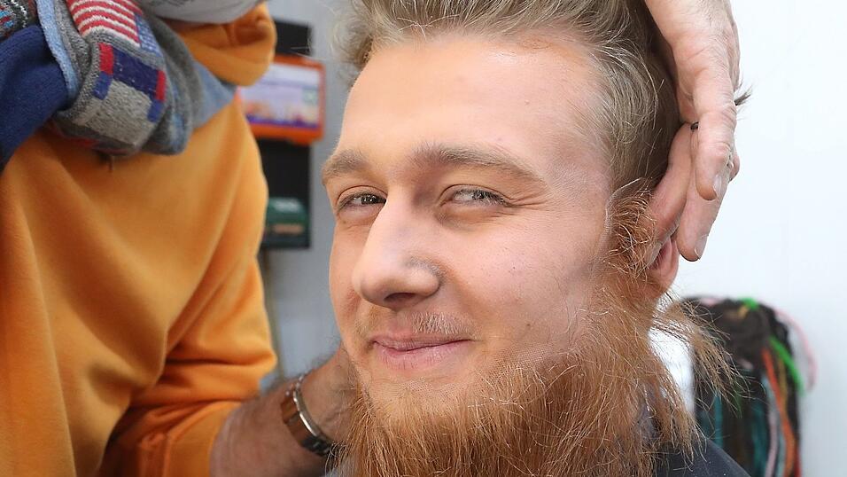 Mit einem nat&uuml;rlichen Klebstoff aus Baumharz befestigt Christian Kurtenbach einen rauen, braunroten Bart an der Haut des Unterkiefers.