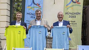 Dominik Krause (v. l.), M&uuml;nchens Oberb&uuml;rgermeister, Markus S&ouml;der (CSU), Ministerpr&auml;sident von Bayern, und Joachim Herrmann (CSU), Bayerns Staatsminister des Innern, f&uuml;r Sport und Integration, stehen nach der Kabinettssitzung mit T-Shirts zur Olympiabewerbung zusammen. Der Schwerpunkt der Konferenz lag im Sport und bei der bayerischen Olympiabewerbung.