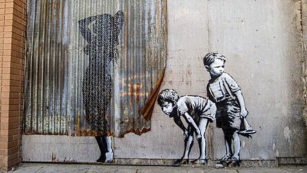 Geht da noch ein bisschen mehr? Banksy lässt zwei Buben den Schatten einer kurvigen Duscherin beobachten - aufgenommen in Dismaland, dem etwas anderen Vergnügungspark auf Zeit in Somerset.