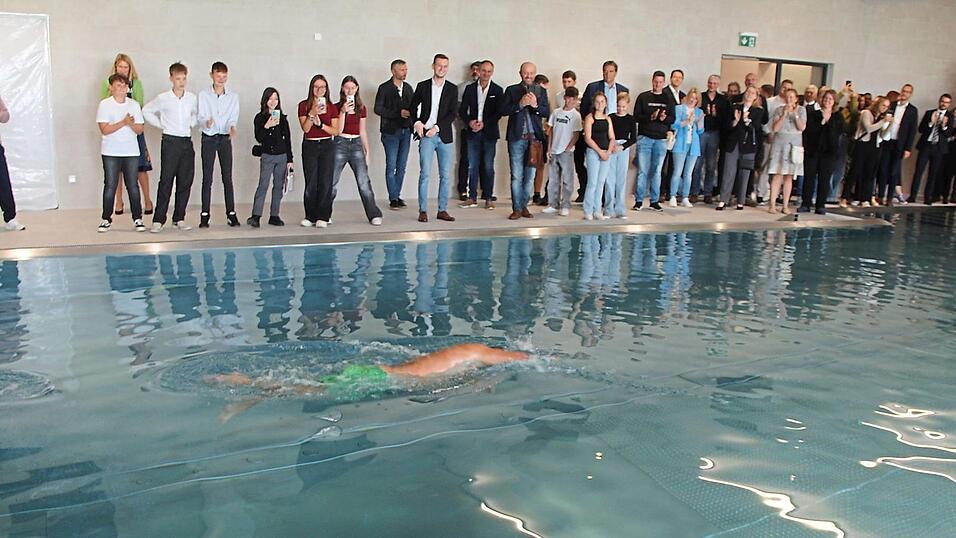 Unter dem Beifall der Gäste der Einweihung schwimmt Direktor Alexander Peintinger die erste Bahn im neuen Hallenbad.