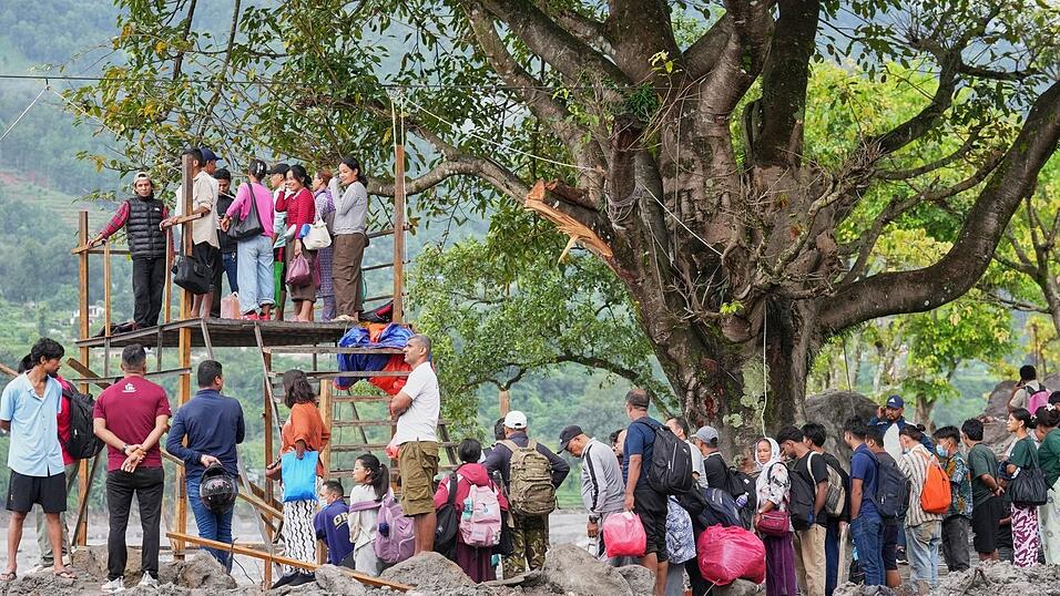 Menschen im Katastrophengebiet in Nepal warten darauf, in eine provisorische Seilbahn besteigen zu können. Menschen im Katastrophengebiet in Nepal warten darauf, in eine provisorische Seilbahn besteigen zu können.