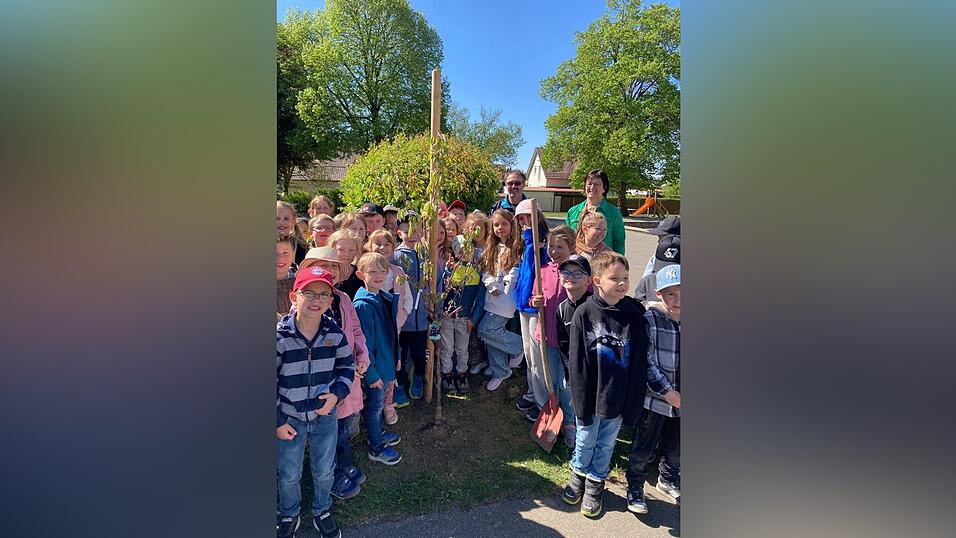 Stolz pr&auml;sentieren die Grundsch&uuml;ler ihren gepflanzten Baum.