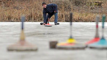Ein Eisstocksch&uuml;tze geht auf einem zugefrorenen Weiher seinem Hobby nach.